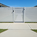 White aluminium fence with a gate on a clear day