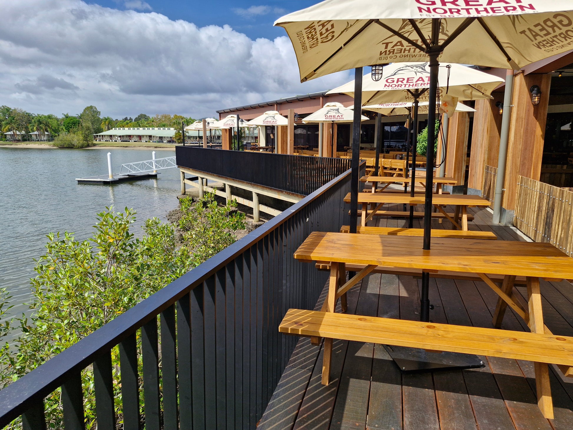 Outdoor seating area with tables and umbrellas by a waterfront