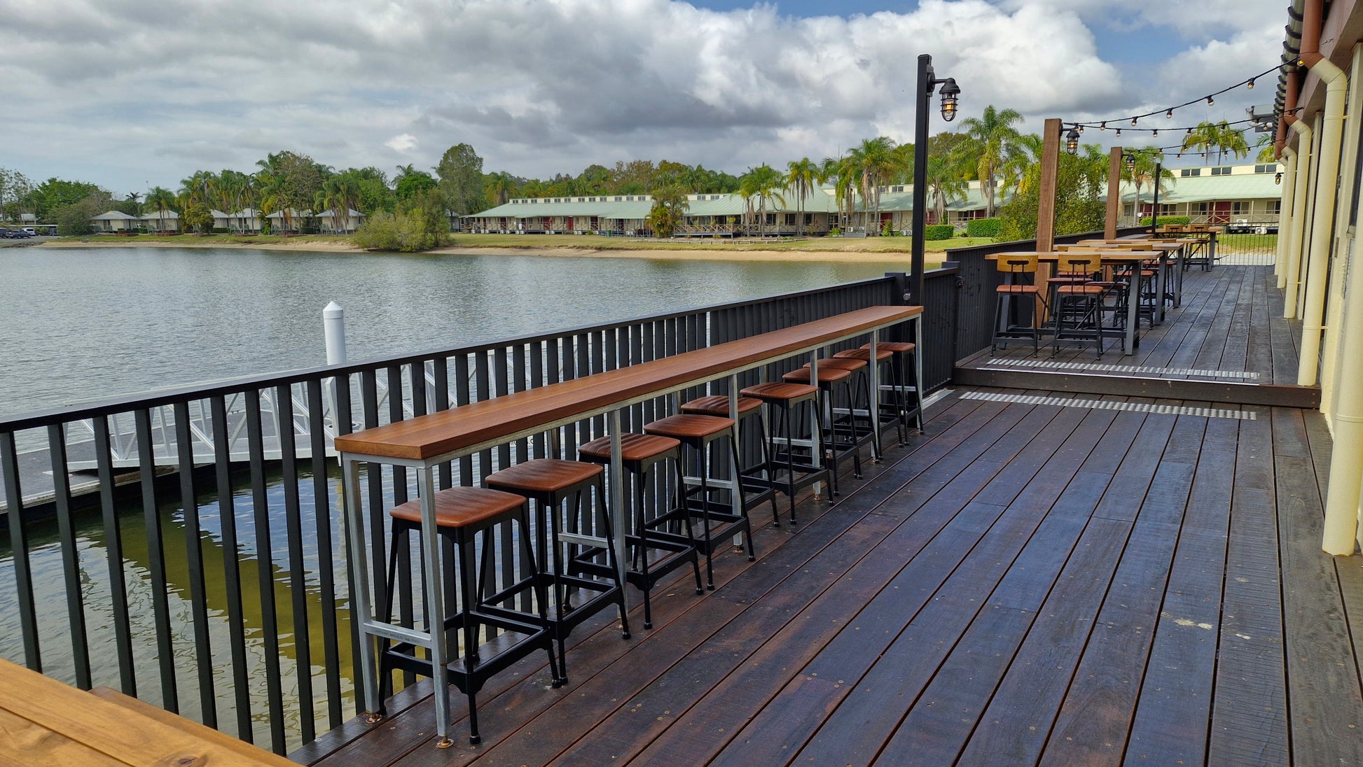 Outdoor deck with tables and stools overlooking a lake and with Visor aluminium balustrade
