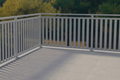 White picket fence on a deck with trees in the background